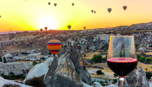 Tourists enjoying a traditional Turkish dinner with mezes and grilled meat at an outdoor restaurant in Cappadocia.