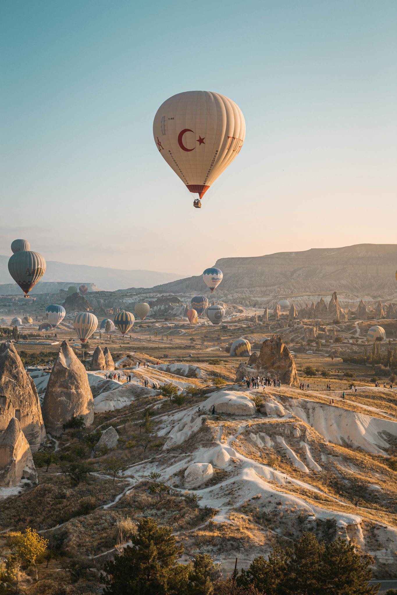 Hot air balloons float above Cappadocia's unique landscape at sunrise, offering a breathtaking aerial view.