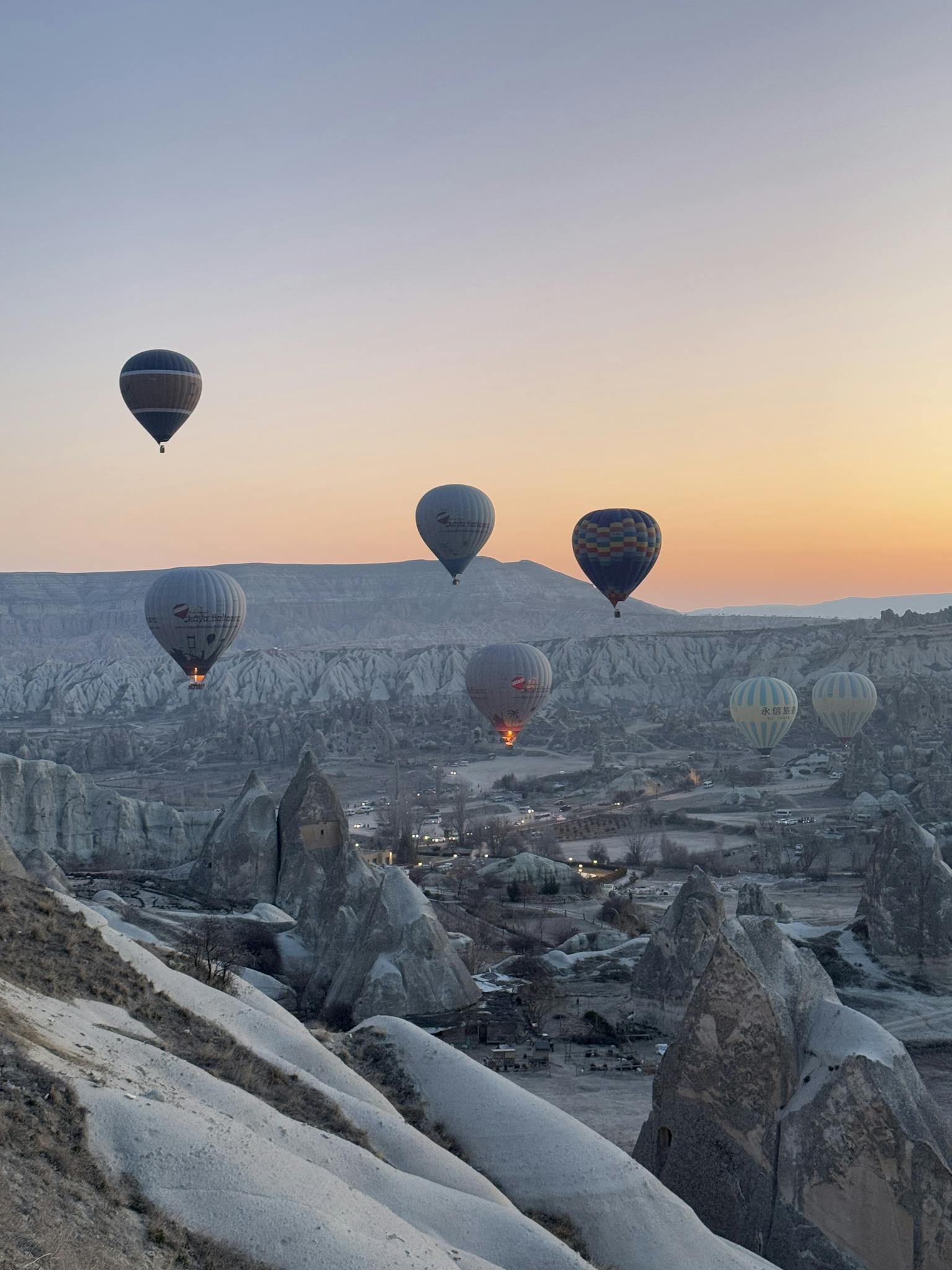 Scenic sunrise view of hot air balloons floating over Cappadocia's unique landscape.